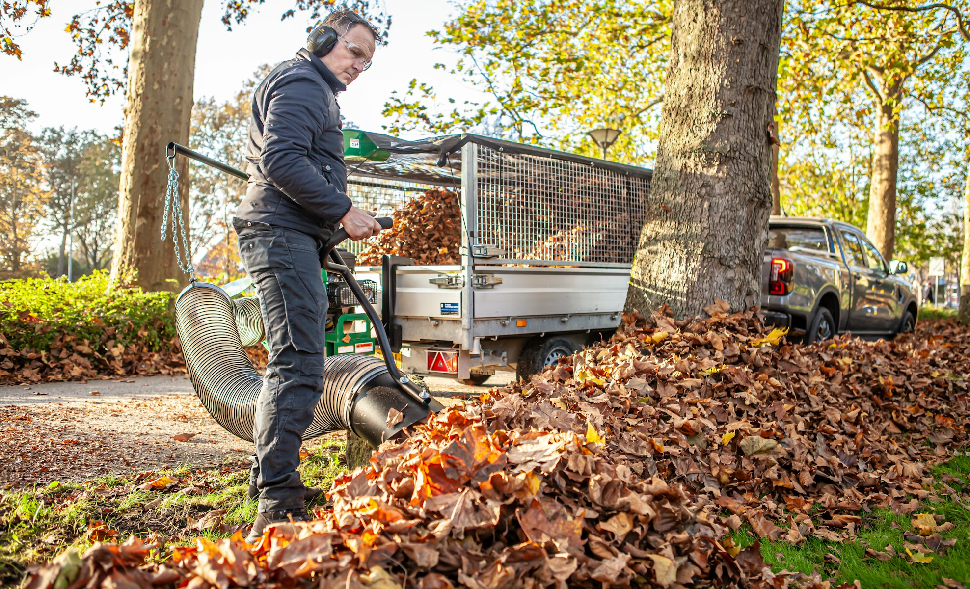 Close up of man vacuuming pile of leaves with debris loader