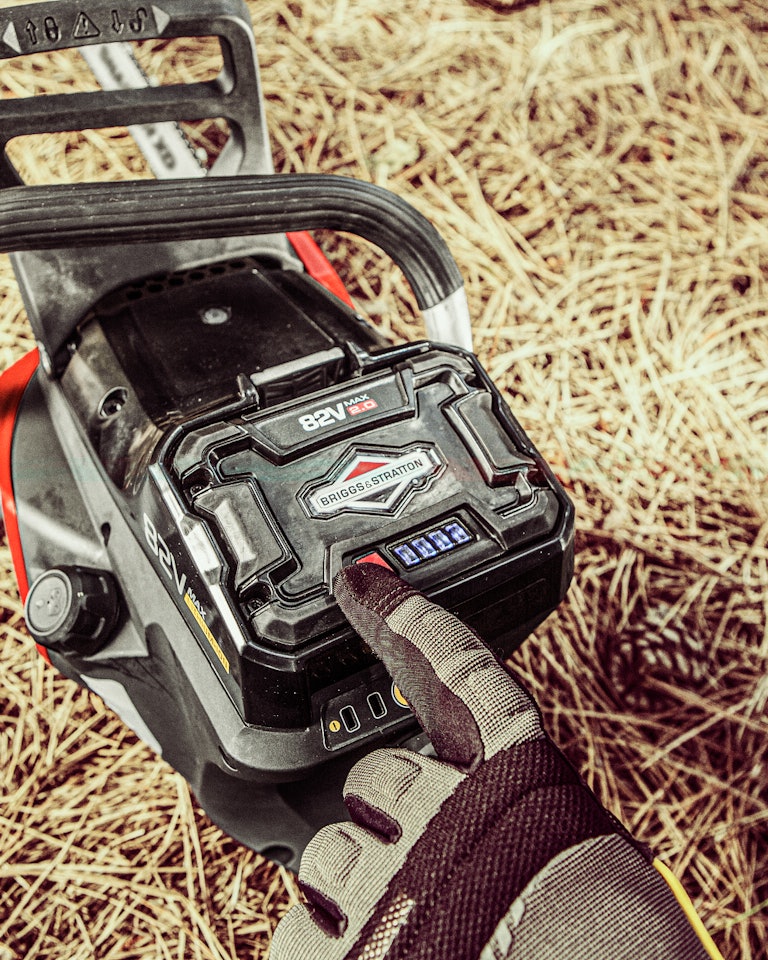Gloved hand pointing at a 82V lithium-ion battery