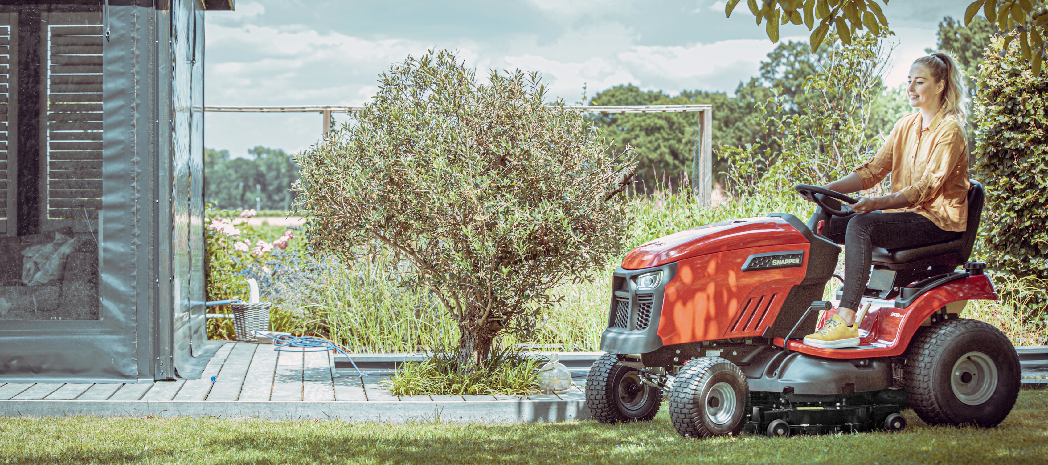 Vrouw maait gras op tuintractor met achteruitworp