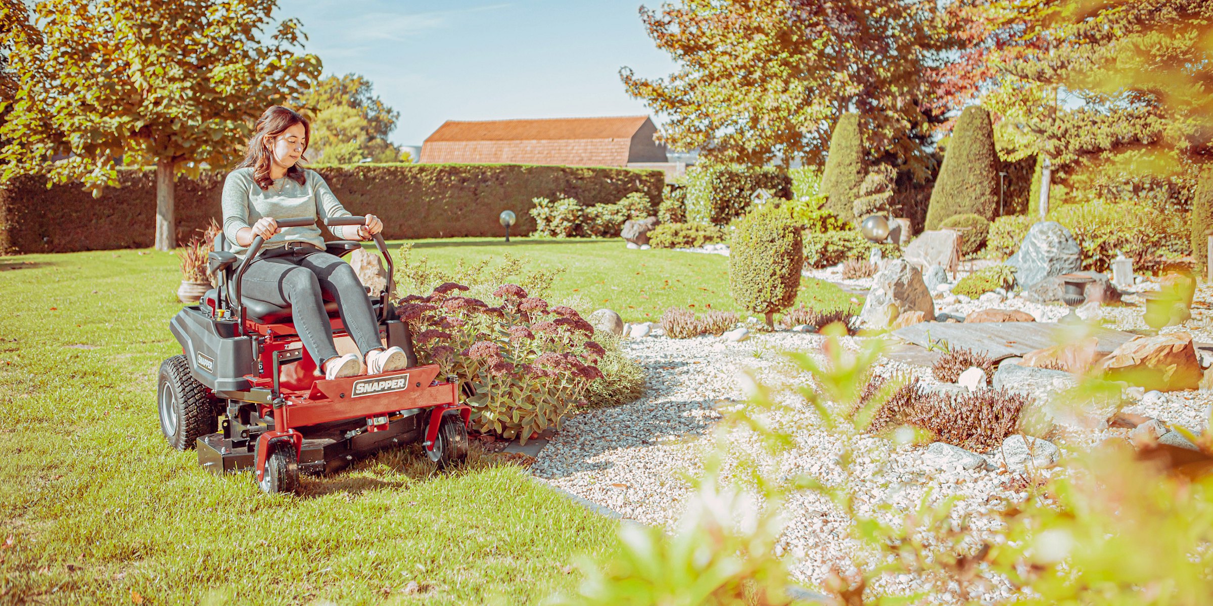 Vrouw maait langs bloembed met zero turn maaier ZTX105